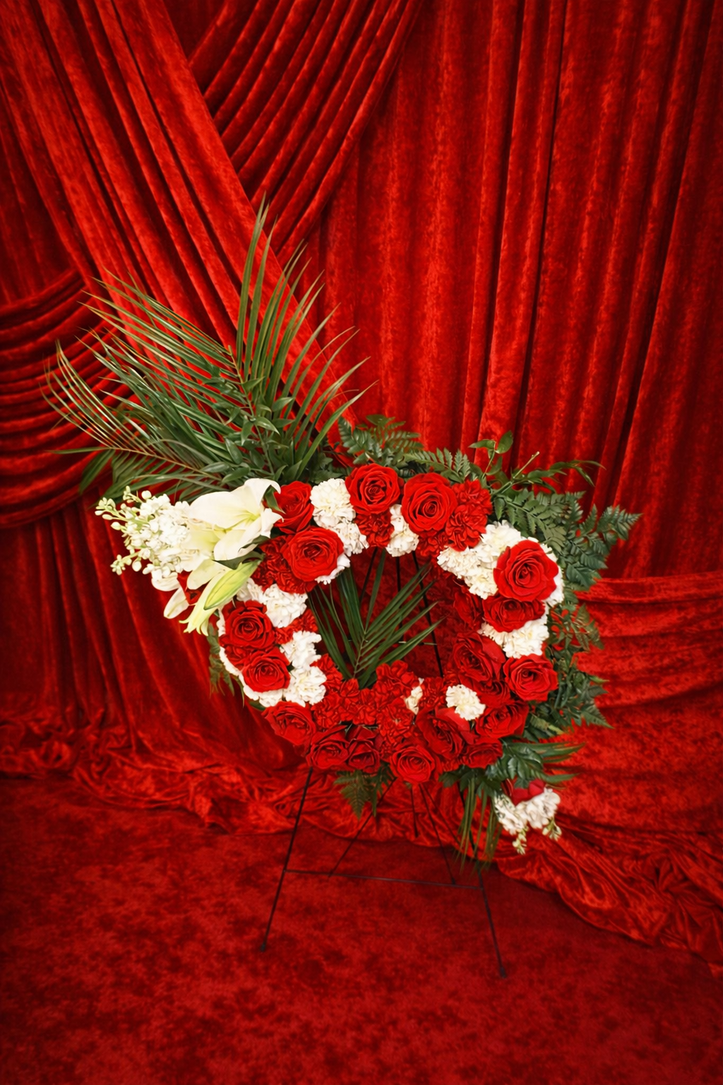 Heart-shaped standing spray of red roses and white carnations on an easel